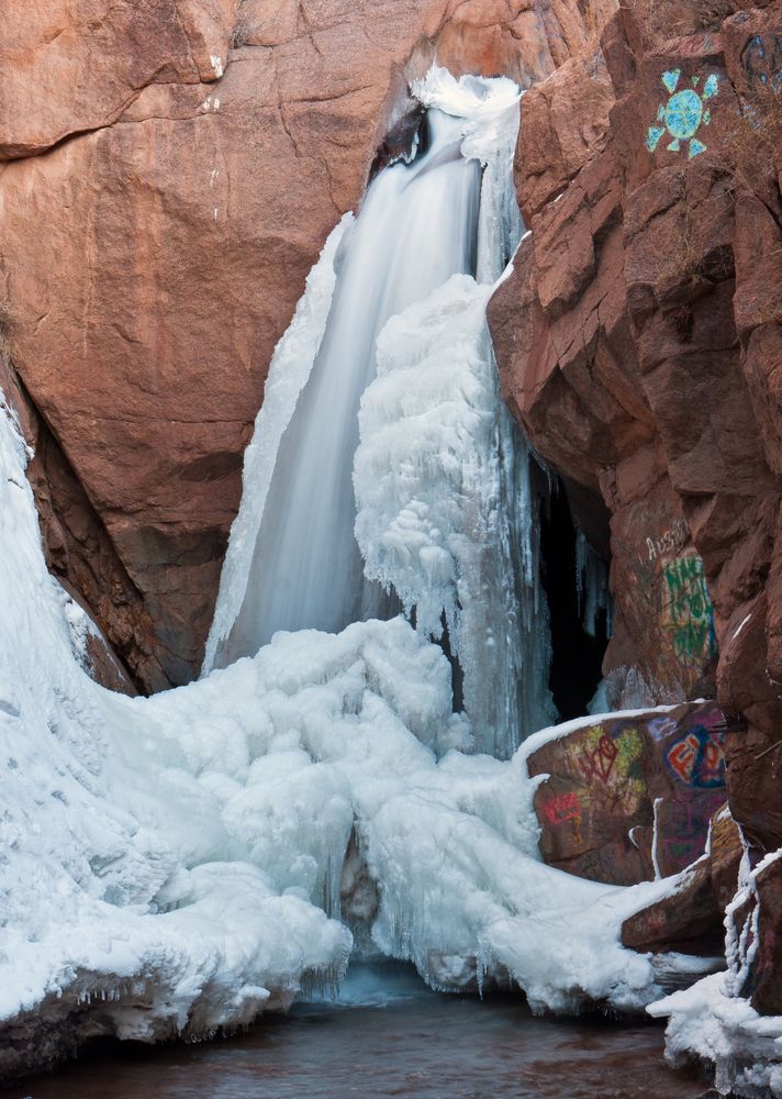 Frozen Rainbow Falls with graffitis on the rock around it