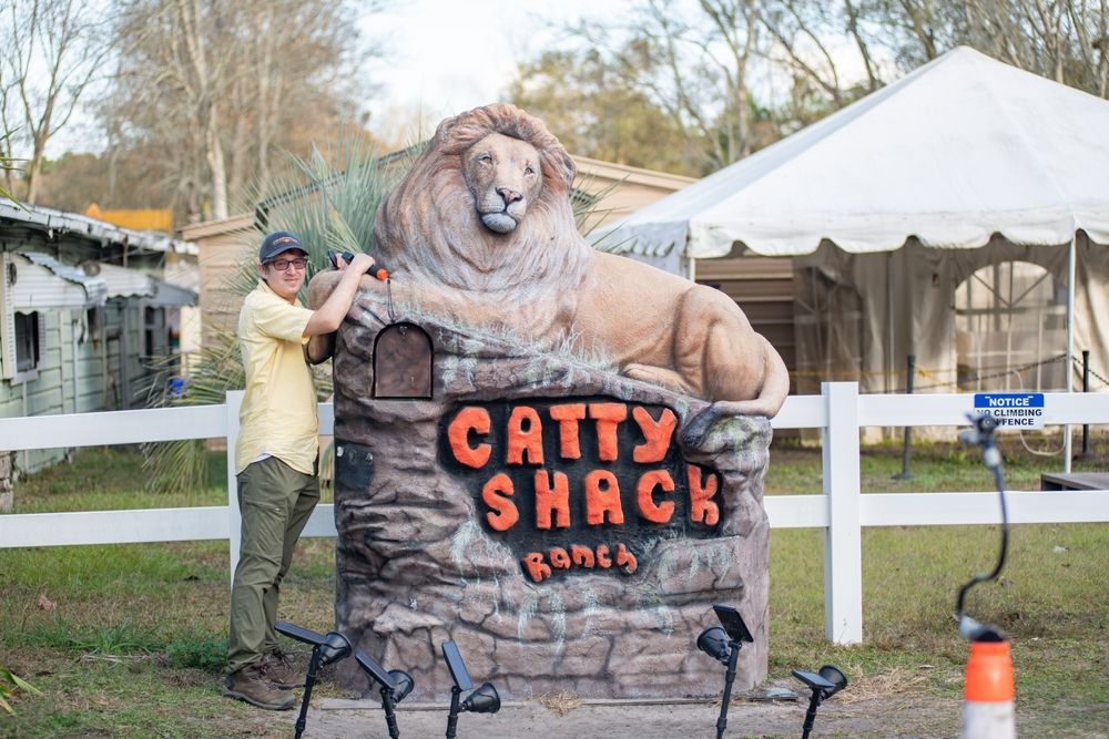 A man posing infront of the Catty Shack Ranch Sanctuary signage