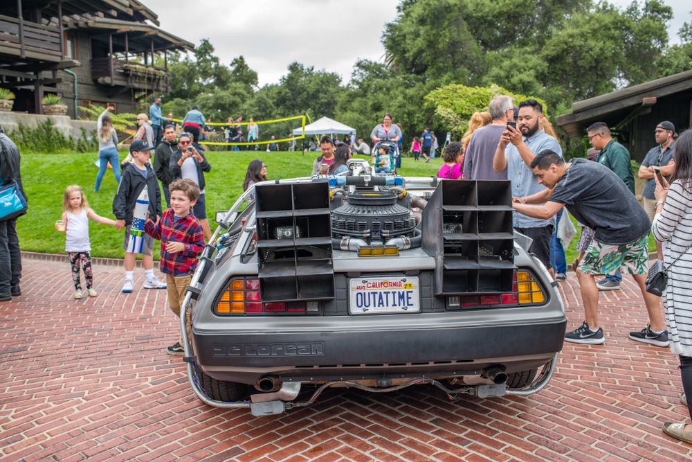 People taking pictures of an exotic car parked in the Gamble House