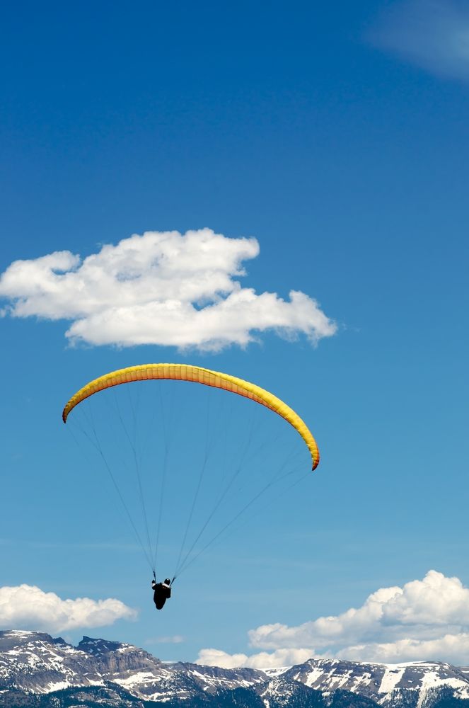 A young man gliding above the mountains at Jackson Hole Paragliding