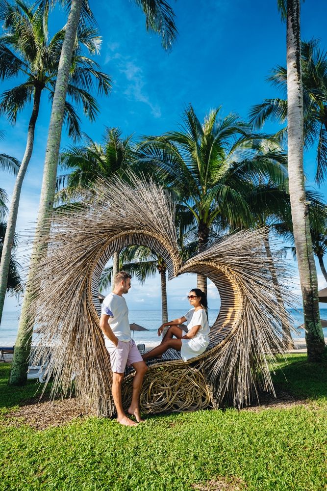 A couple posing on a heart-shaped chair at Hat Karon Noi Beach