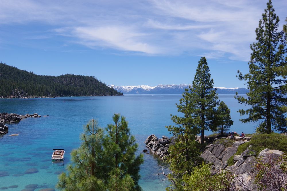 Landscape view of Lake Tahoe with rocks, and green-coloured trees.