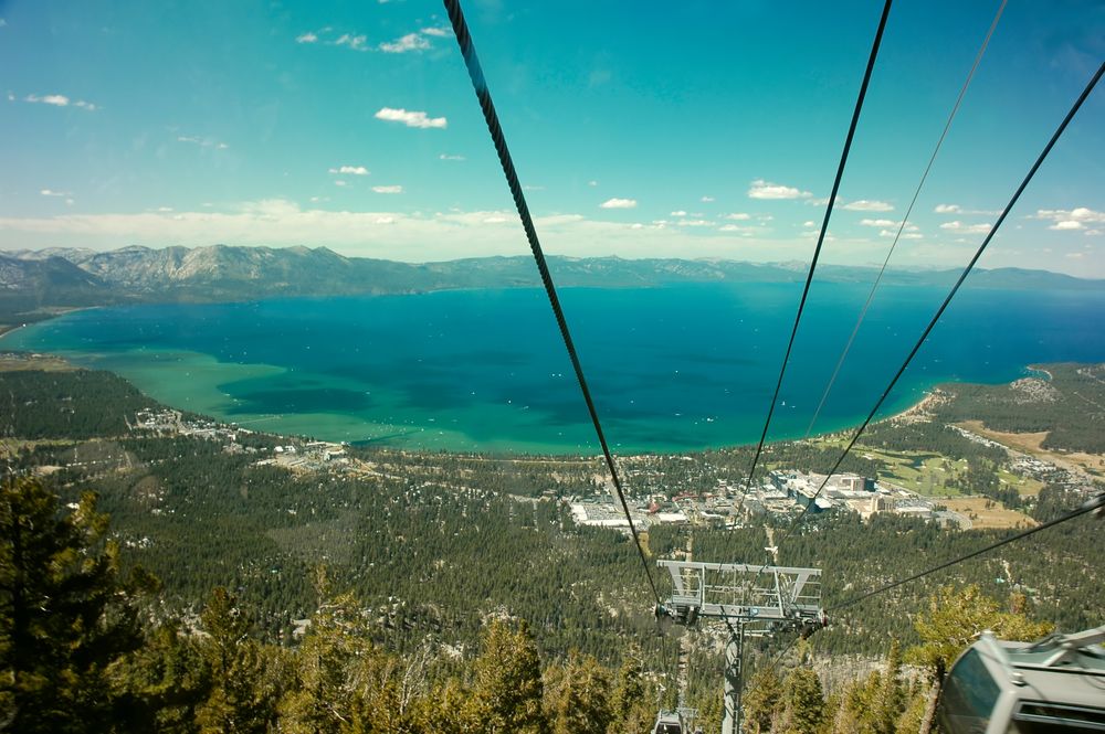 Aerial view of Lake Tahoe showing the deep blue waters, and the land surrounding it.