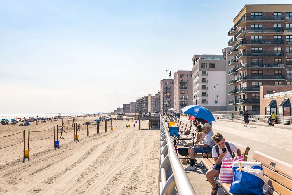 People enjoying the view of the beach from the benches at Long Beach Boardwalk