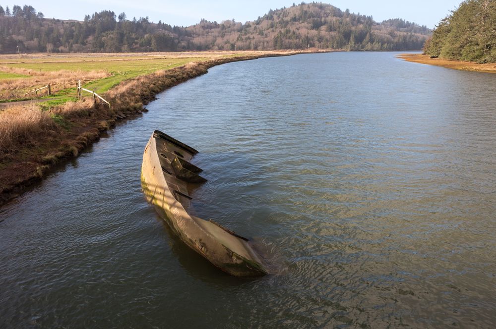 A boat submerged in a river at Nestucca Bay National Wildlife Refuge