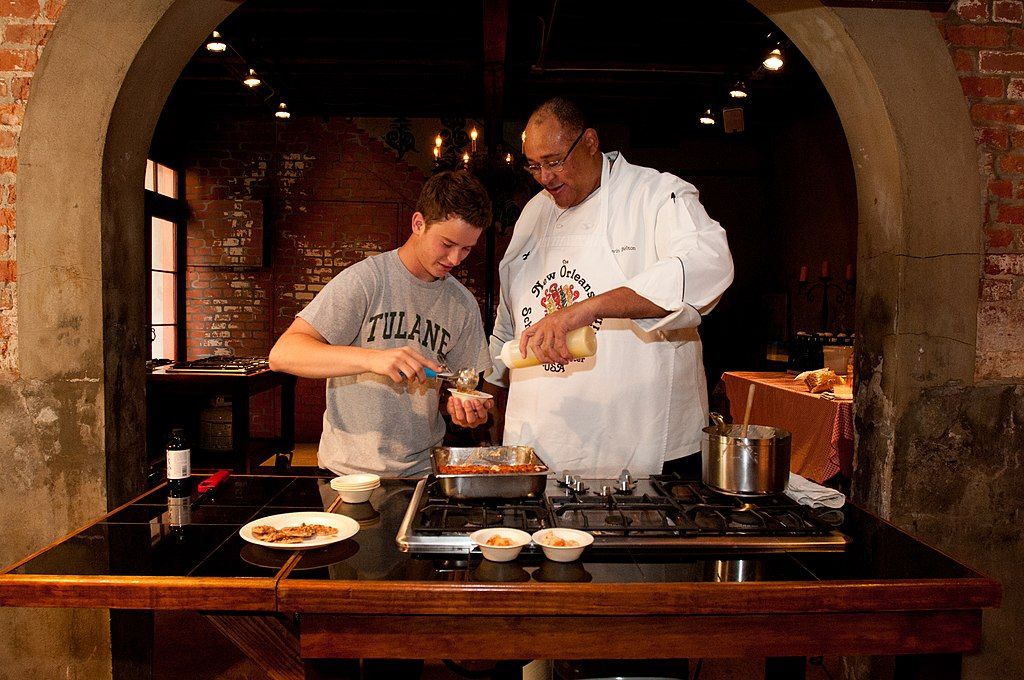 A chef teaching a boy to cook at New Orleans School of Cooking