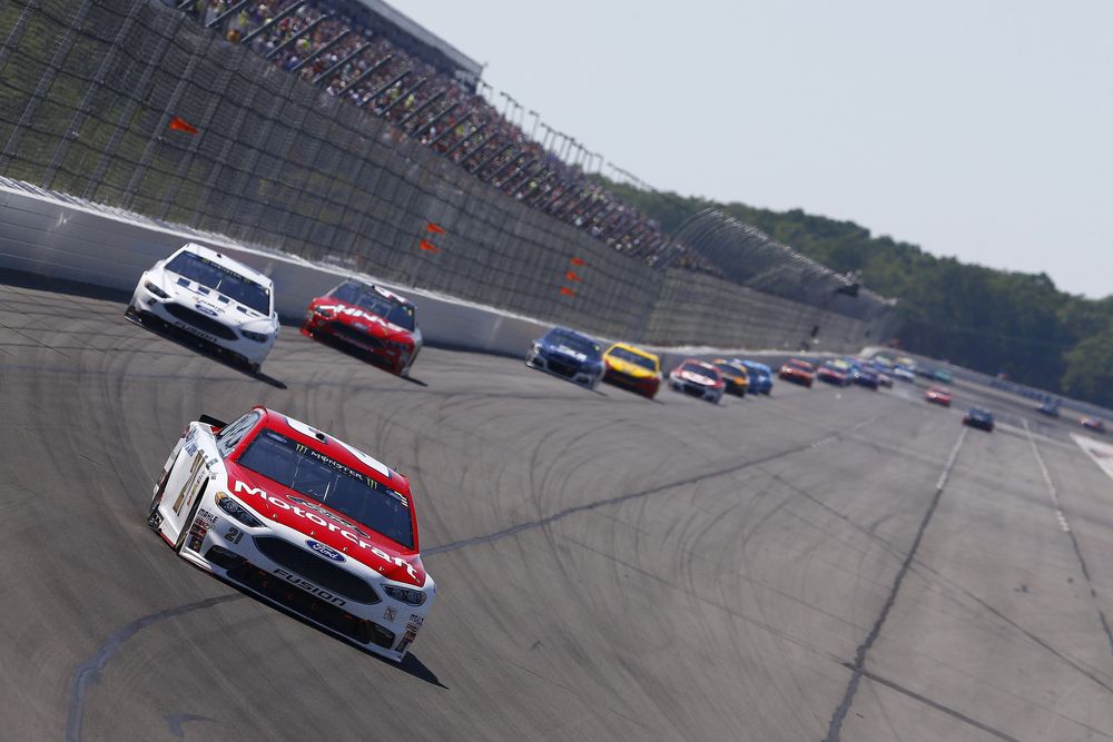 White and red race car on the lead, with other race cars behind it.