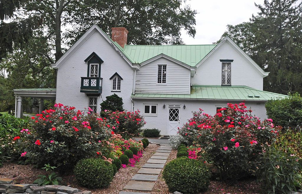 Beautiful white building of Tudor Hall surrounded by colorful flowers