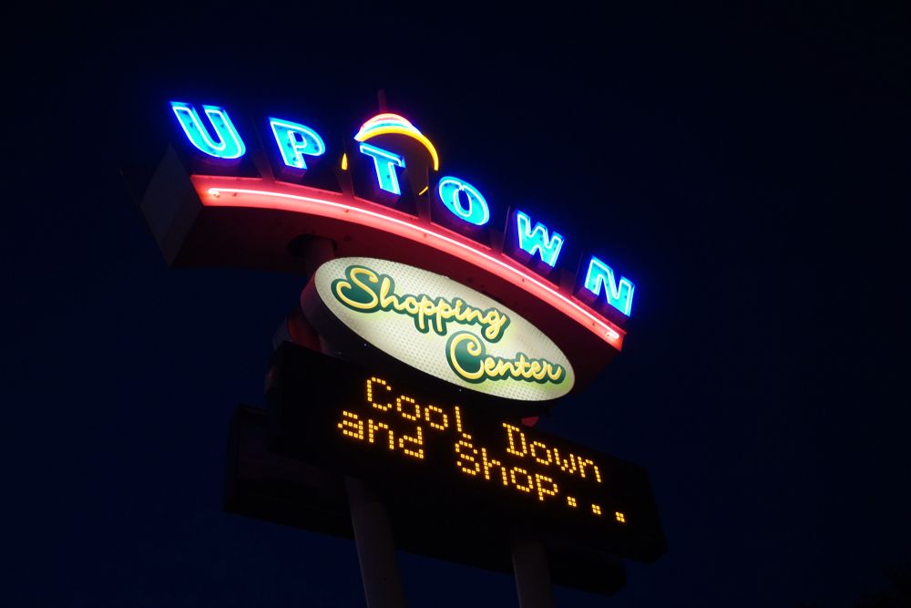Neon sign of Uptown Shopping Center shinning in the dark night sky