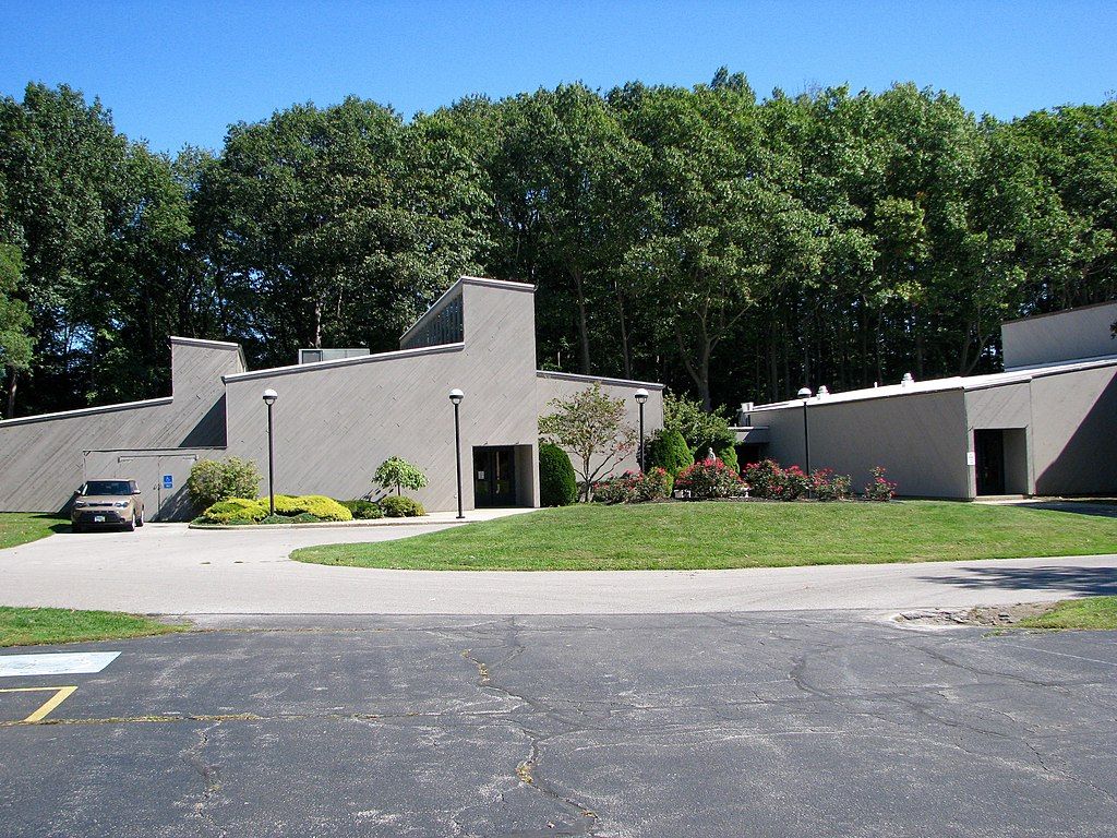 Exterior of the Ashtabula arts center with tall, green trees behind it.