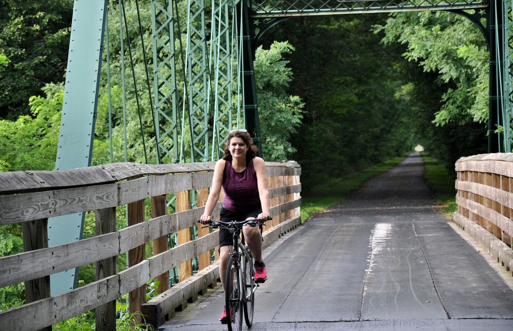 A woman riding her bicycle over metal bridge on western reserve greenway trail.