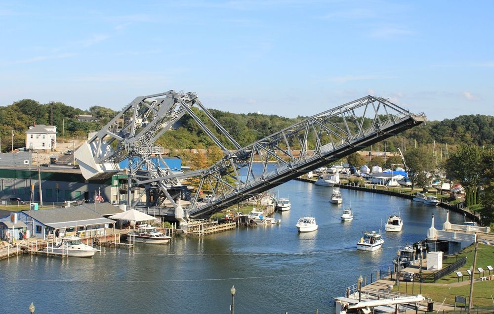 Ashtabula lift bridge during a clear, sunny day. Several boats can be seen afloat the body of water.