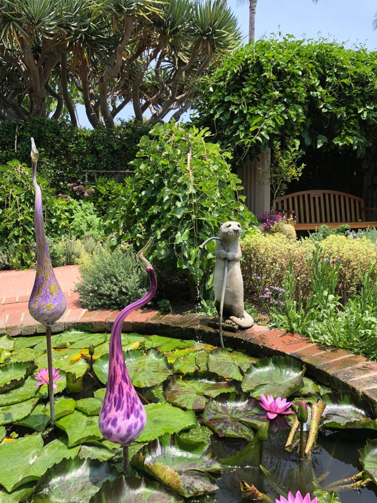 A otter sculpture holding a hose at Sherman Library & Gardens