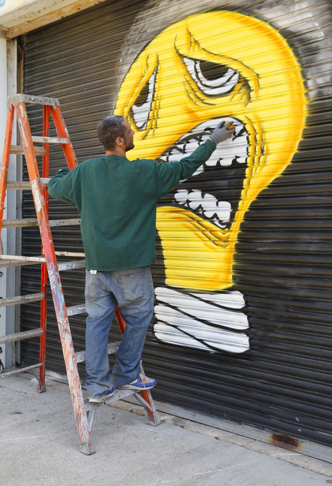 A street artist painting a mural at Bushwick Collective