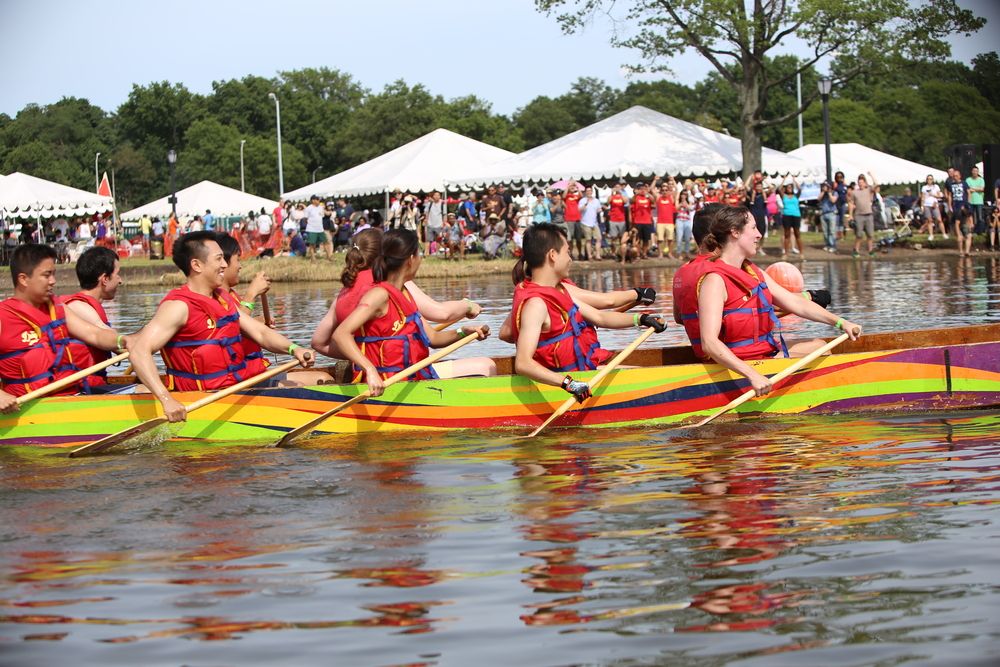 Participants rowing a colourful boat on a body of water.
