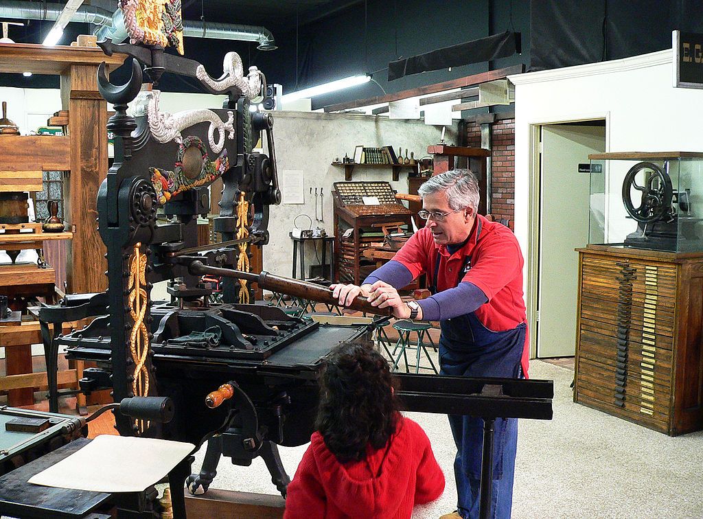 A person demonstrating how to use an antique printing press in International Printing Museum