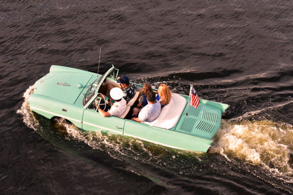 People riding an Amphicar on a lake