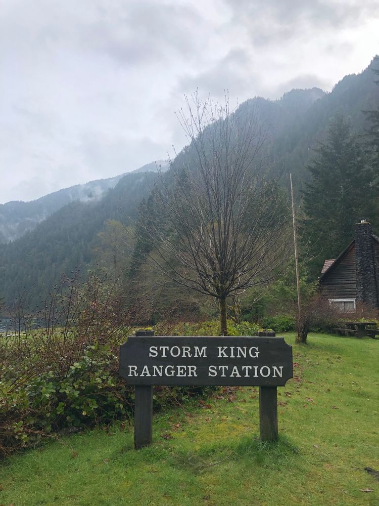 Wooden name sign of storm king ranger station standing on green grass.
