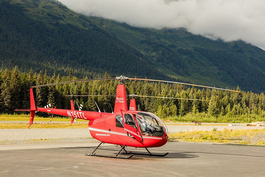 A red helicopter parked near a mountain.