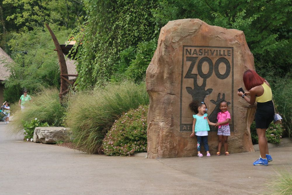 People taking pictures in front of Nashville Zoo's sign