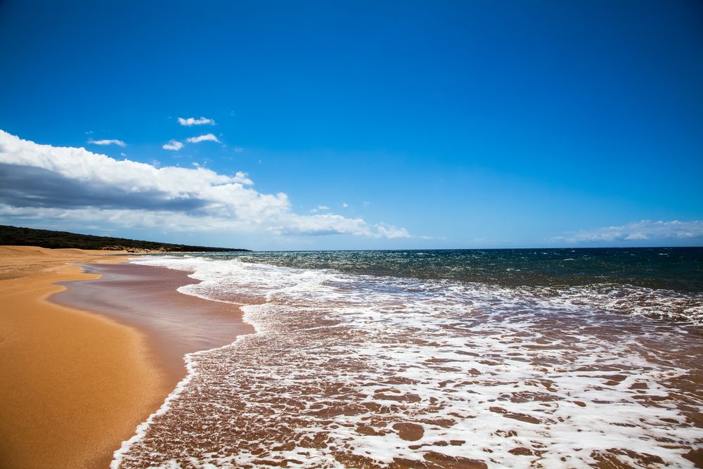 Calm waves covering Polihua Beach's sand