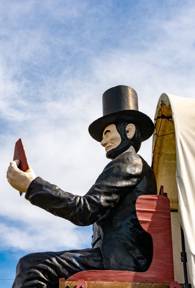 Sculpture of Abraham Lincoln sitting on the Railsplitter Covered Wagon