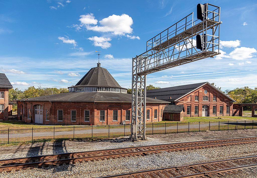 Exterior view of the martinsburg roundhouse near a train track.