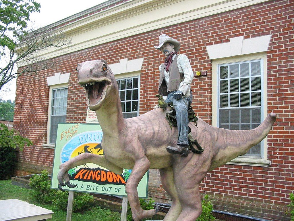 Dinosaur sculpture beside Dinosaur Kingdom II welcome sign