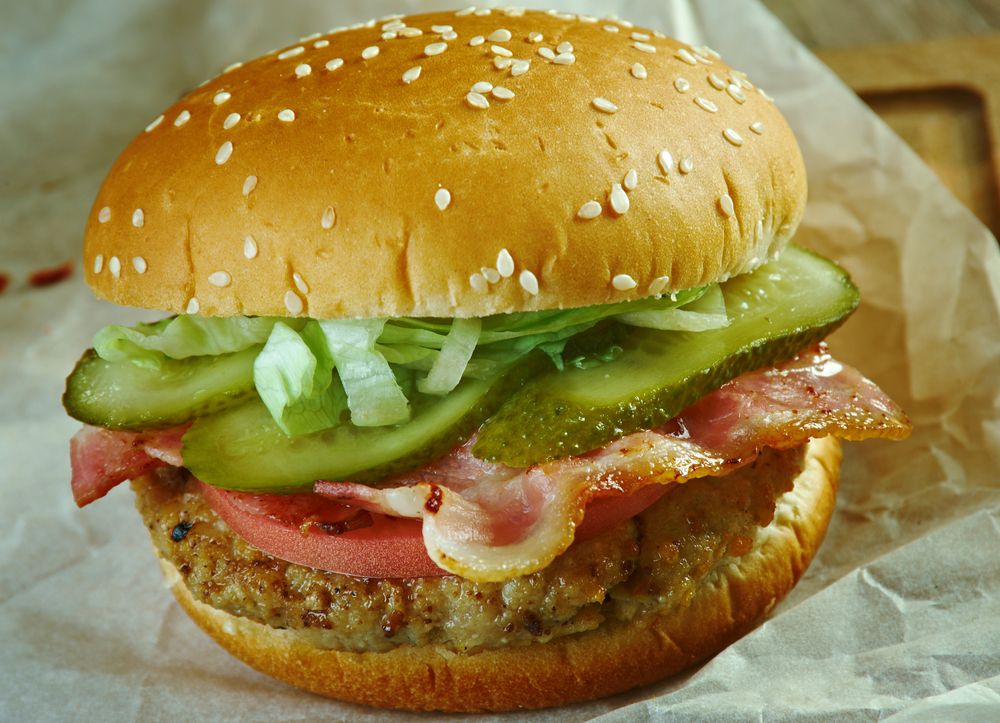 A hodad's burger with a patty, pickles, greens and tomato.