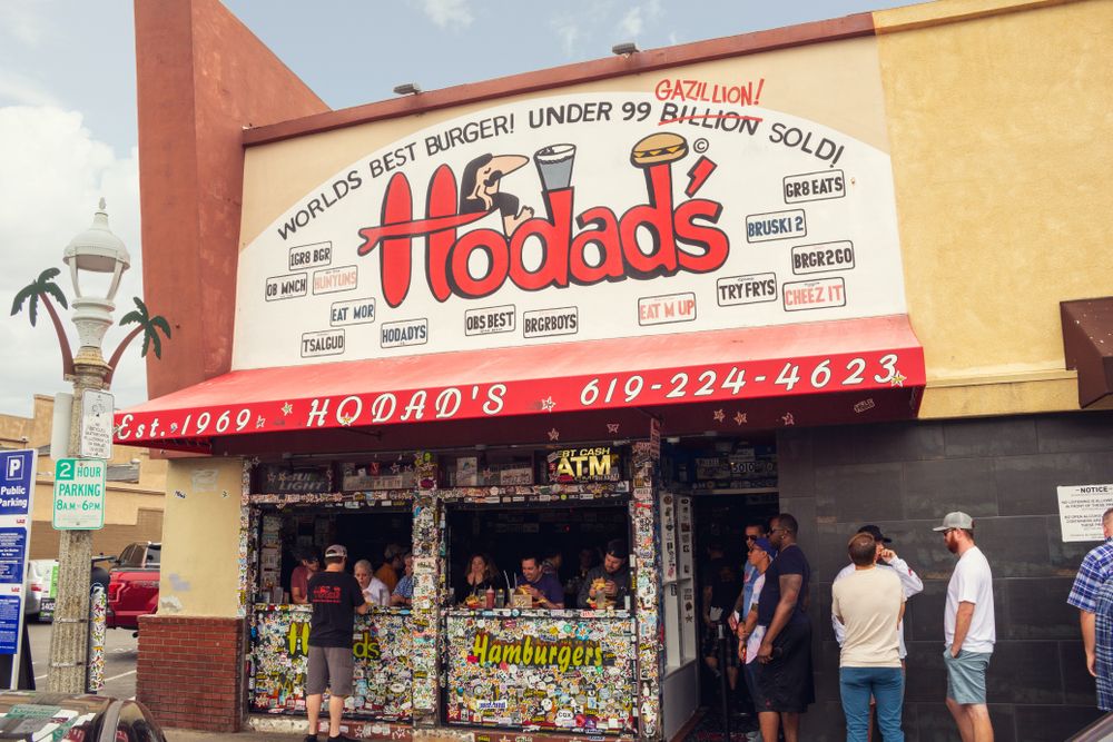 Exterior of Hodad's burger with the name sign and delivery number on top.