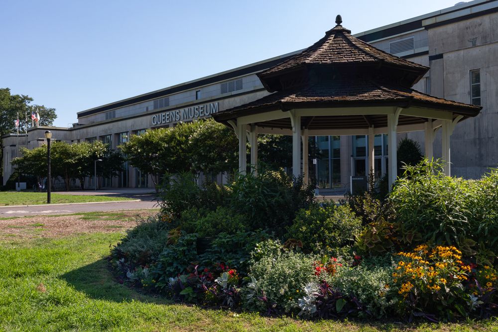 A gazebo surrounded with plants in front of Queens Museum of Art