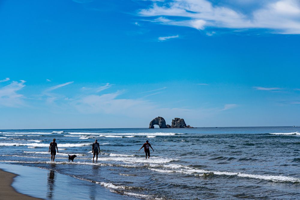 People playing at the beach with the Twin Rocks at the background.