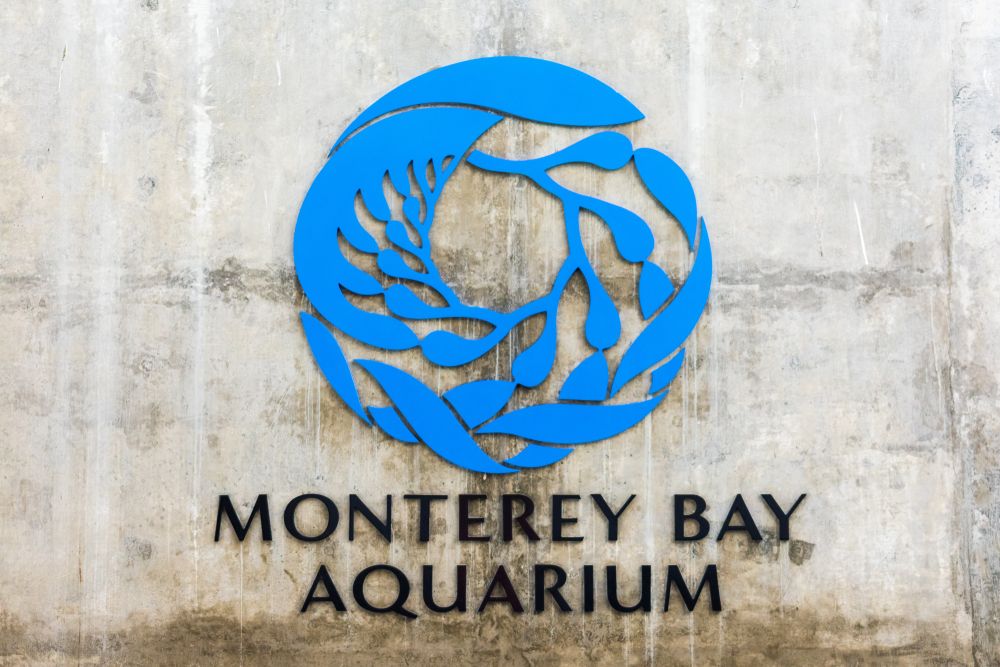 Monterey bay aquarium name sign with a blue circle on top.