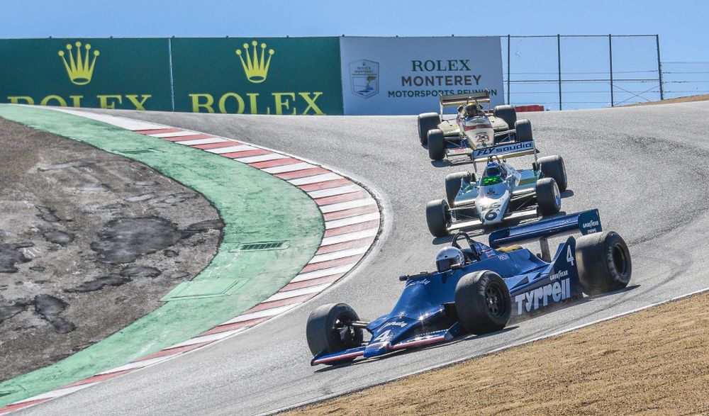 Three race cars racing on the raceway.