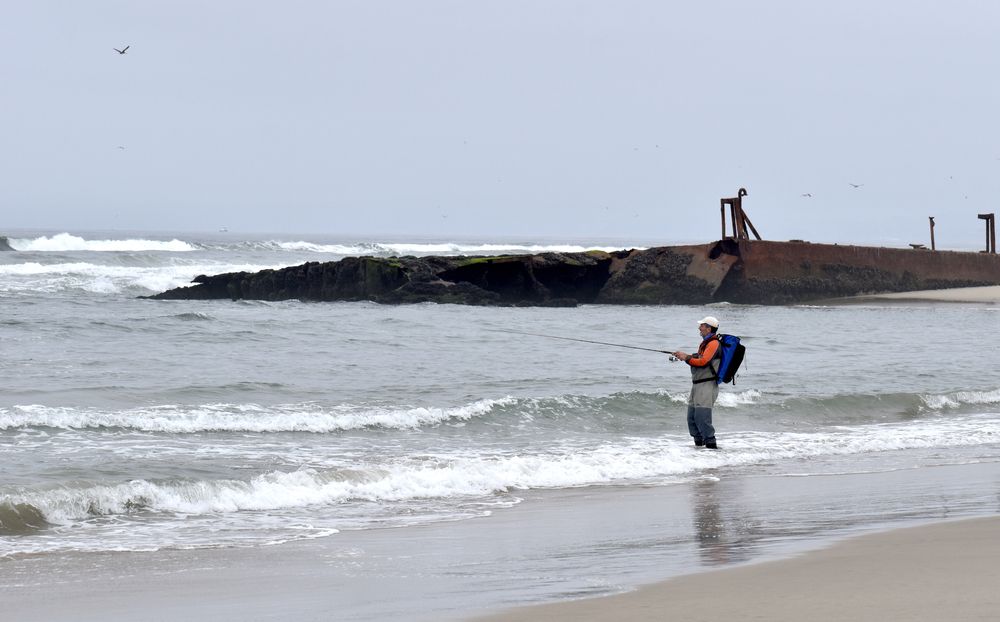 A man fishing on the salinas river during a cloudy day.