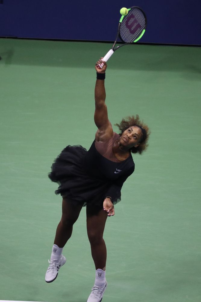 Serena Williams holding a tennis racket, about to hit the ball.